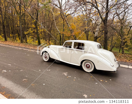 White vintage car driving on wet city road. Retro transport, classic elegance and timeless automotive heritage 134118311