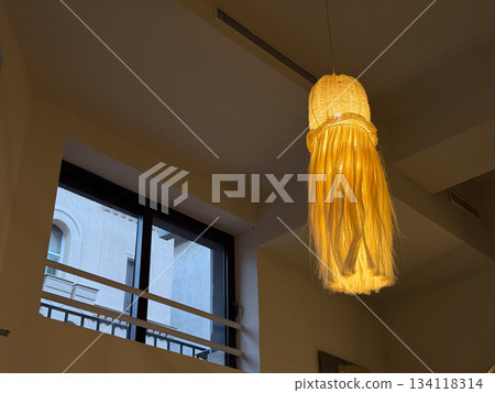 Warm hanging lamp with long textured shade. Interior lighting, cozy ambiance and creative decorative design element 134118314