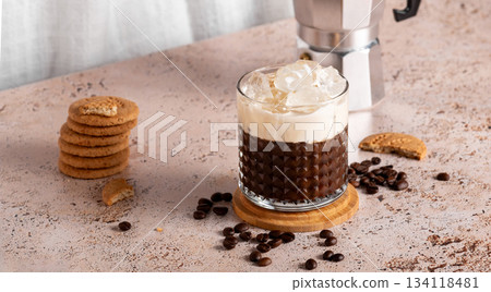Iced coffee with espresso moka pot and cookies on textured countertop Iced coffee with espresso moka pot and cookies on textured countertop 134118481