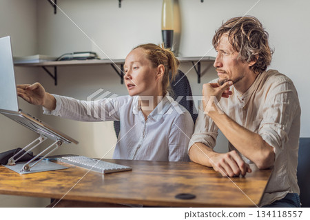 Man and woman working together in their home office, discussing tasks and collaborating on a project. Modern remote work, teamwork and productivity concept, representing communication, focus and 134118557