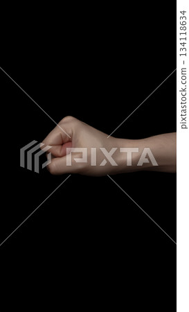 一隻緊握的拳頭漂浮在黑色背景上 / 一個簡單的視覺符號,象徵意志和力量 一隻緊握的拳頭漂浮在黑色背景上 / 一個簡單的視覺符號,象徵意志和力量 134118634