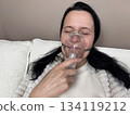 Adult woman using a home nebulizer inhaler while sitting in a cozy bedroom, respiratory treatment at home for breathing relief, healthcare and medical therapy concept, realistic lifestyle scene 134119212