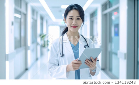 Hyperrealistic photo of a smiling female doctor holding a digital tablet standing in a modern, high-tech hospital corridor 134119248