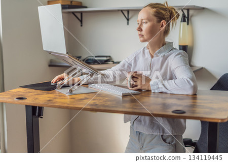 Woman standing at her desk and working in her home office, focused on tasks and productivity. Modern remote work, healthy posture and professional lifestyle concept, representing balance, efficiency 134119445