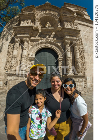 A family of four posing in front of a large building A family of four posing in front of a large building 134120278