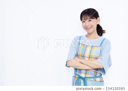 一位家庭主婦面帶微笑，雙手抱胸，若有所思。 134120393