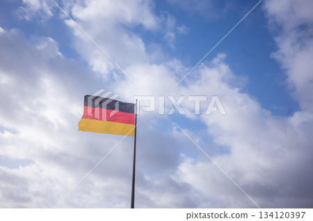 [Germany] The German flag waving in the sky of the capital Berlin and cloudy skies with a hint of sunshine 134120397