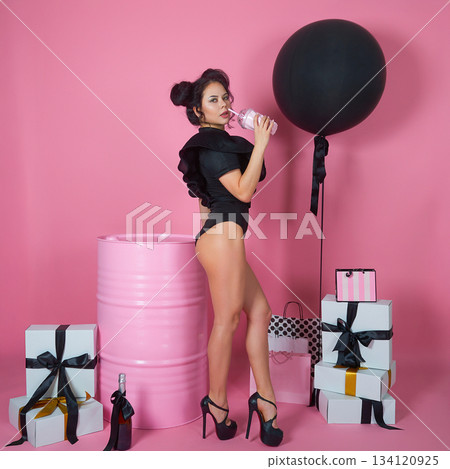 Elegant Woman with Gifts and Black Balloon in Pink Studio 134120925
