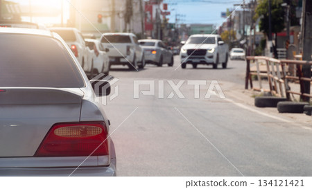 Rear side view of car in the traffic jam at day time. Many car drive behind the queue arranged in a curved line. With blurred of other car driving on the opposite lens on asphalt road at day. 134121421