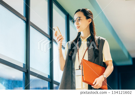 Business woman operating a smartphone in the office Business woman operating a smartphone in the office 134121602