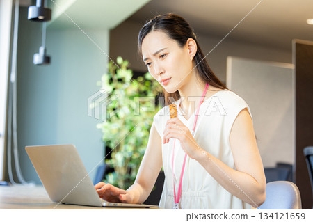 Woman eating a protein bar in the office Woman eating a protein bar in the office 134121659