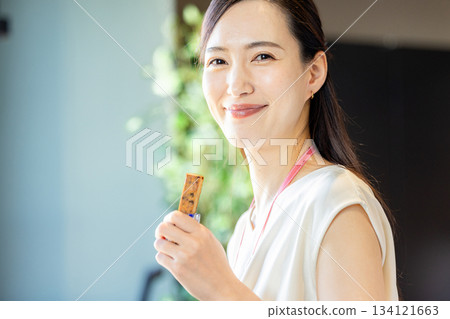 Woman eating a protein bar in the office 134121663
