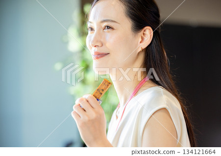 辦公室裡，一個女人正在吃蛋白棒。 134121664