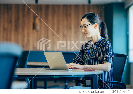 Middle-aged business woman operating a personal computer in the office Middle-aged business woman operating a personal computer in the office 134121665