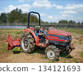 [Katori City, Chiba] An agricultural scene of a tillage tractor surrounded by flowers and soft light. 134121693