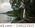 Whispers of Nature: Woman in White Dress Contemplating by the Lake 134121915