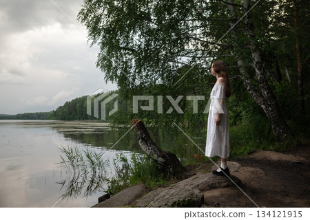 Whispers of Nature: Woman in White Dress Contemplating by the Lake 134121915