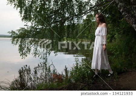 Elegance by the Lake: Woman in White Off-Shoulder Dress Among Birch Trees 134121933