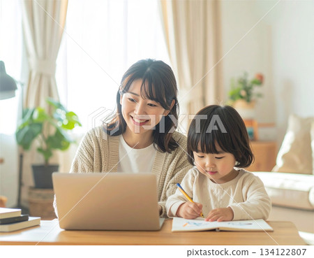 A mother working from home and her child doing homework. Parents and children spending time together smiling in a bright living room. A mother working from home and her child doing homework. Parents and children spending time together smiling in a bright living room. 134122807
