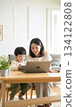 A mother working from home and her child doing homework. Parents and children spending time together smiling in a bright living room. 134122808