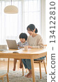 A mother working from home and her child doing homework. Parents and children spending time together smiling in a bright living room. 134122810