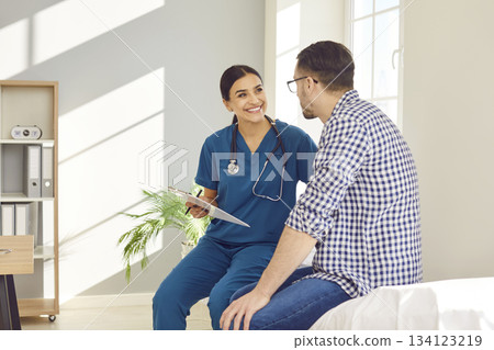 Smiling Female Doctor Advises Male Patient in Hospital Office Smiling Female Doctor Advises Male Patient in Hospital Office 134123219