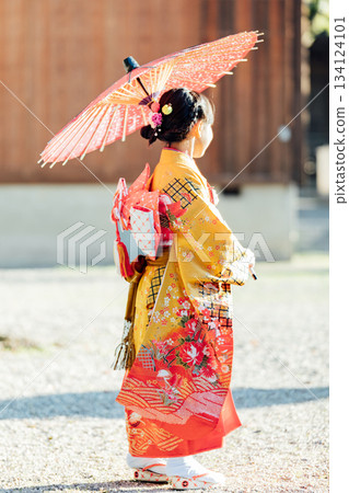 一位女孩在神社裡撐著一把日式傘，向七五三祈禱。 134124101
