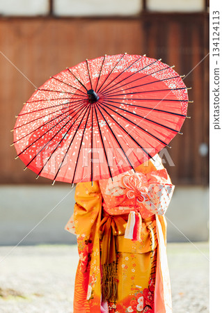 A girl praying at a shrine with a Japanese umbrella for Shichi-Go-San A girl praying at a shrine with a Japanese umbrella for Shichi-Go-San 134124113
