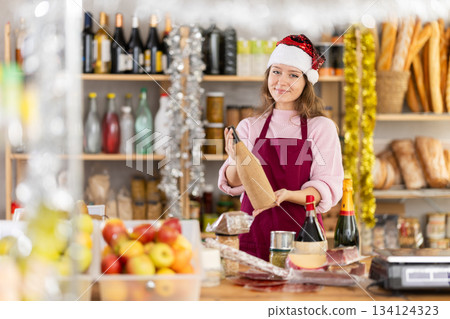 Young female seller with wine in grocery store 134124323