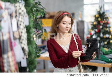 Young woman choosing ankle boots on Christmas tree background Young woman choosing ankle boots on Christmas tree background 134124348