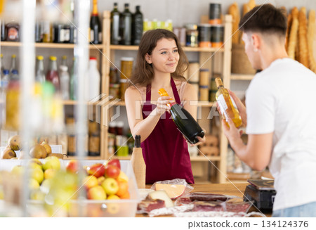 Young woman seller offers wine to man 134124376