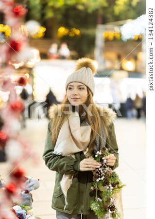 At outdoor fair girl choose and looks at something, Xmas atmosphere 134124382