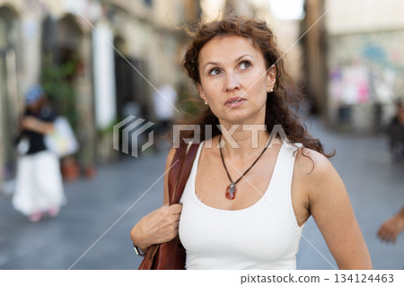 Woman in casual clothes walking through summer city street 134124463