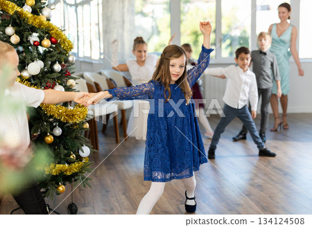 Little children practicing waltz dance in school-hall decorated with Christmas-tree Little children practicing waltz dance in school-hall decorated with Christmas-tree 134124508
