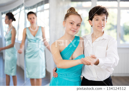 Teenage girl and boy practicing waltz in dance hall with female mentor Teenage girl and boy practicing waltz in dance hall with female mentor 134124512