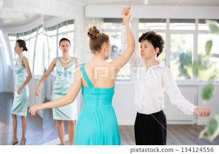 Adolescent dance duo, boy and girl, refining slow foxtrot with female coach 134124556