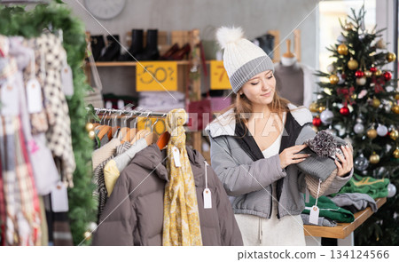 Young woman choosing winter hats on sale Young woman choosing winter hats on sale 134124566