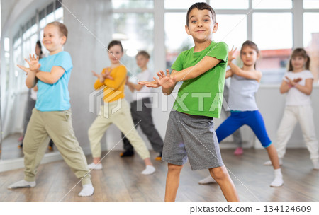 Children studying modern style dances with female teacher in dance class Children studying modern style dances with female teacher in dance class 134124609
