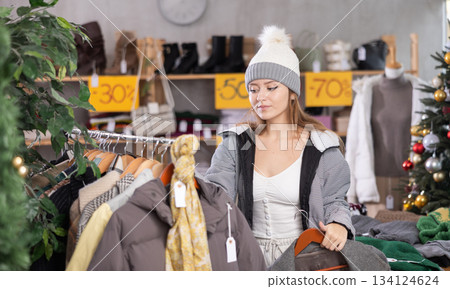 Young woman choosing coats and jackets at Christmas sale Young woman choosing coats and jackets at Christmas sale 134124624
