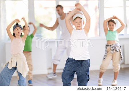 Young happy boy and group of positive children practicing energetic hip hop movements at dance school 134124647