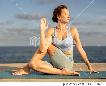Ardha Matsyendrasana yoga pose - woman doing yoga On beach 134124675