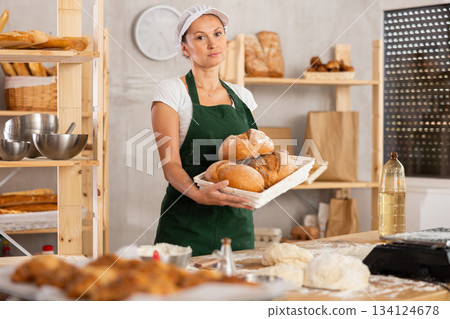 Bakery woman employee holds ready made bread of bread on tray 134124678