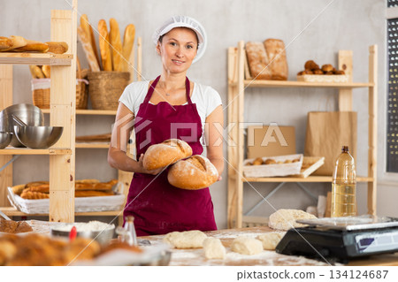Woman baker holding bread 134124687