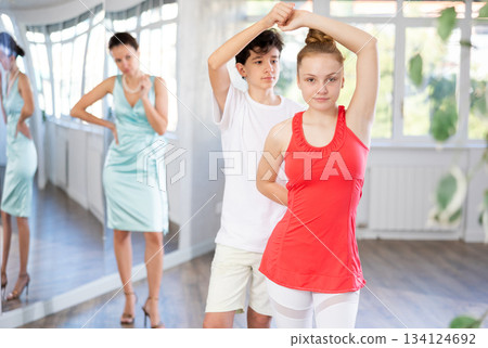 Experienced dance teacher teaching ballroom dancing to a couple of teenagers in studio 134124692