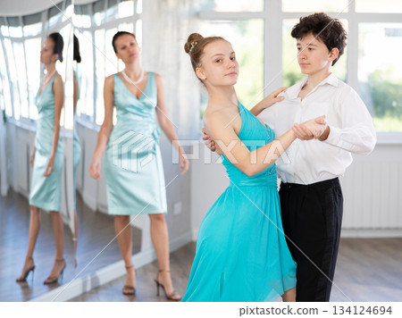 Experienced female dancer teaches tango to pair of teenagers in ballroom 134124694