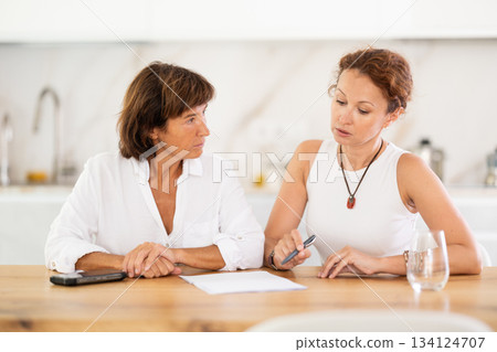 Two woman at table and trying to figure out finance problem and thinking about bills at home Two woman at table and trying to figure out finance problem and thinking about bills at home 134124707