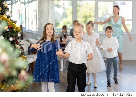 Preteen children in elegant outfits practicing partner dance in Christmas studio Preteen children in elegant outfits practicing partner dance in Christmas studio 134124725