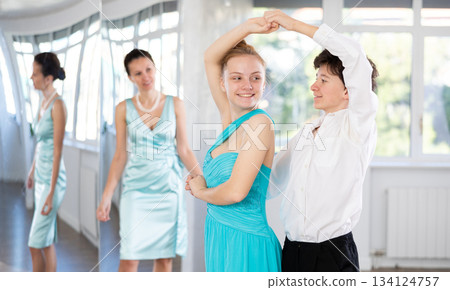 Couple of teenagers in festive clothes learn to dance latin american dance Bachata in studio under the guidance of teacher 134124757