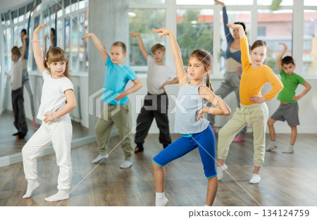 Children training modern dance moves together in studio under the guidance of teacher 134124759