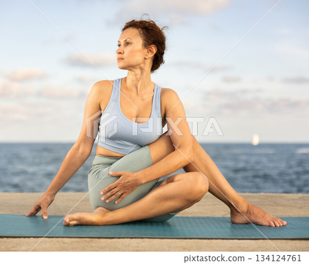 Woman performing Ardha Matsyendrasana position yoga training Woman performing Ardha Matsyendrasana position yoga training 134124761